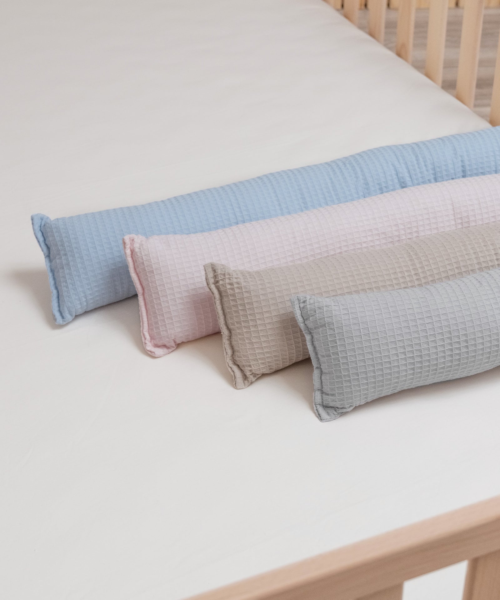 Vier Farben der Bettschlange aus Waffelpiqué liegen nebeneinander auf dem Bett.