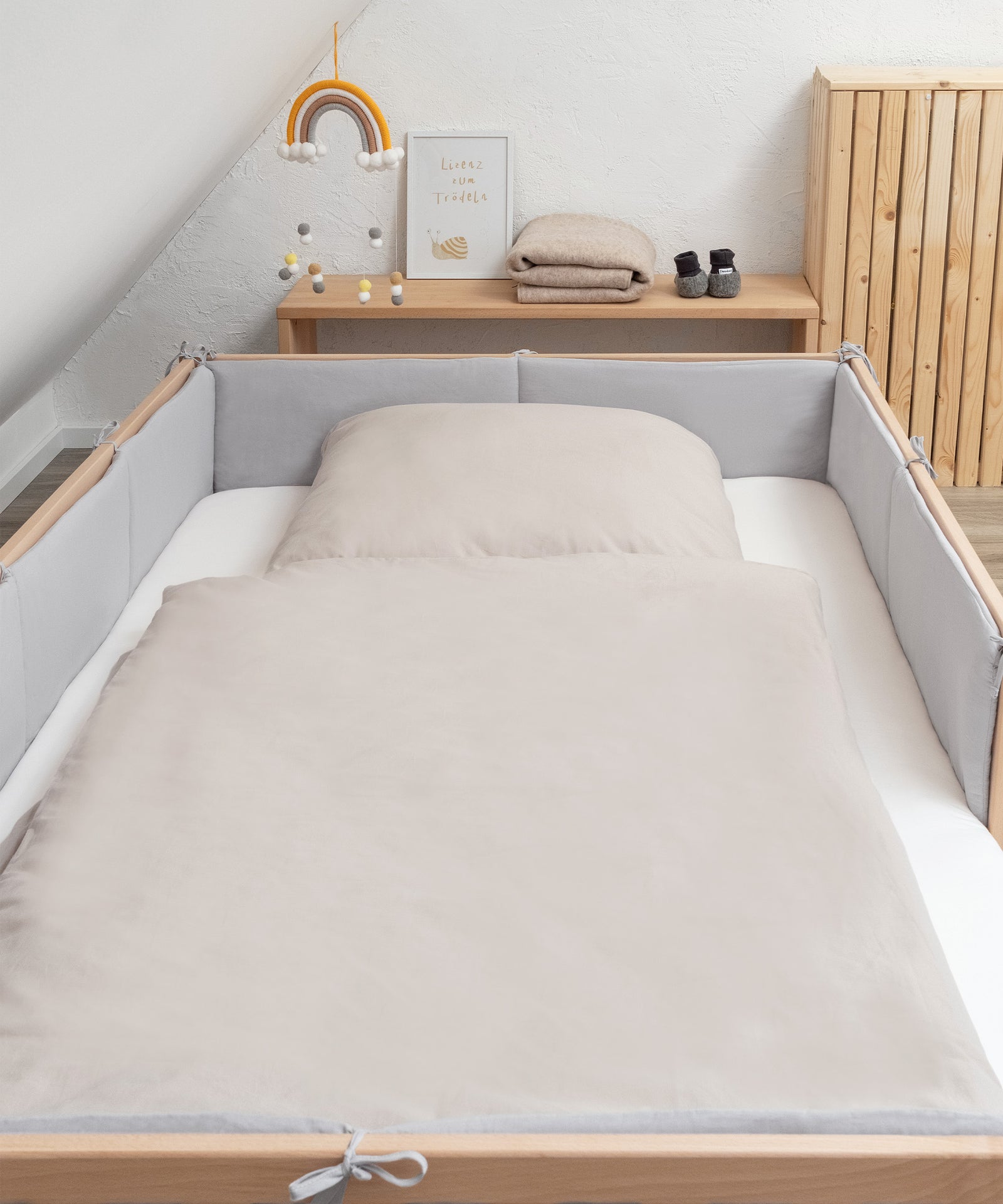 Zwei praktische Größen*Die Bettumrandung passt perfekt zu all unseren Ehrenkind Betten mit den Maßen 200 × 90 cm und 200 × 120 cm.|Bett der Größe 200 mal 120 cm mit Bettumrandung hellgrau und Renforcé Bettwäsche in Beige.