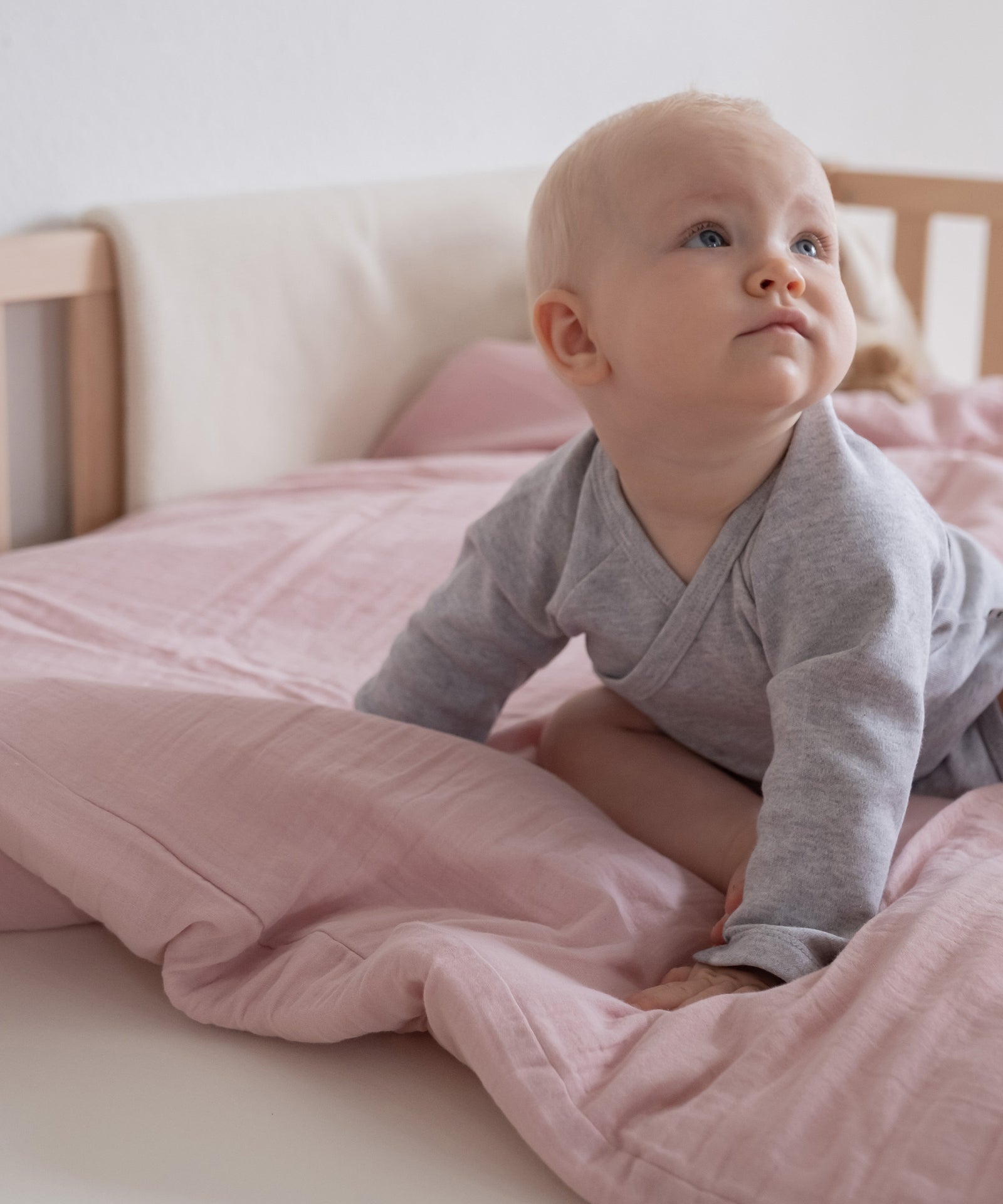 Atmungsaktiv*Unsere Bettwäsche besteht aus kuschelweicher und hautfreundlicher Bio-Baumwolle, die die Haut atmen lässt.|Baby sitzt auf der Bettwäsche.