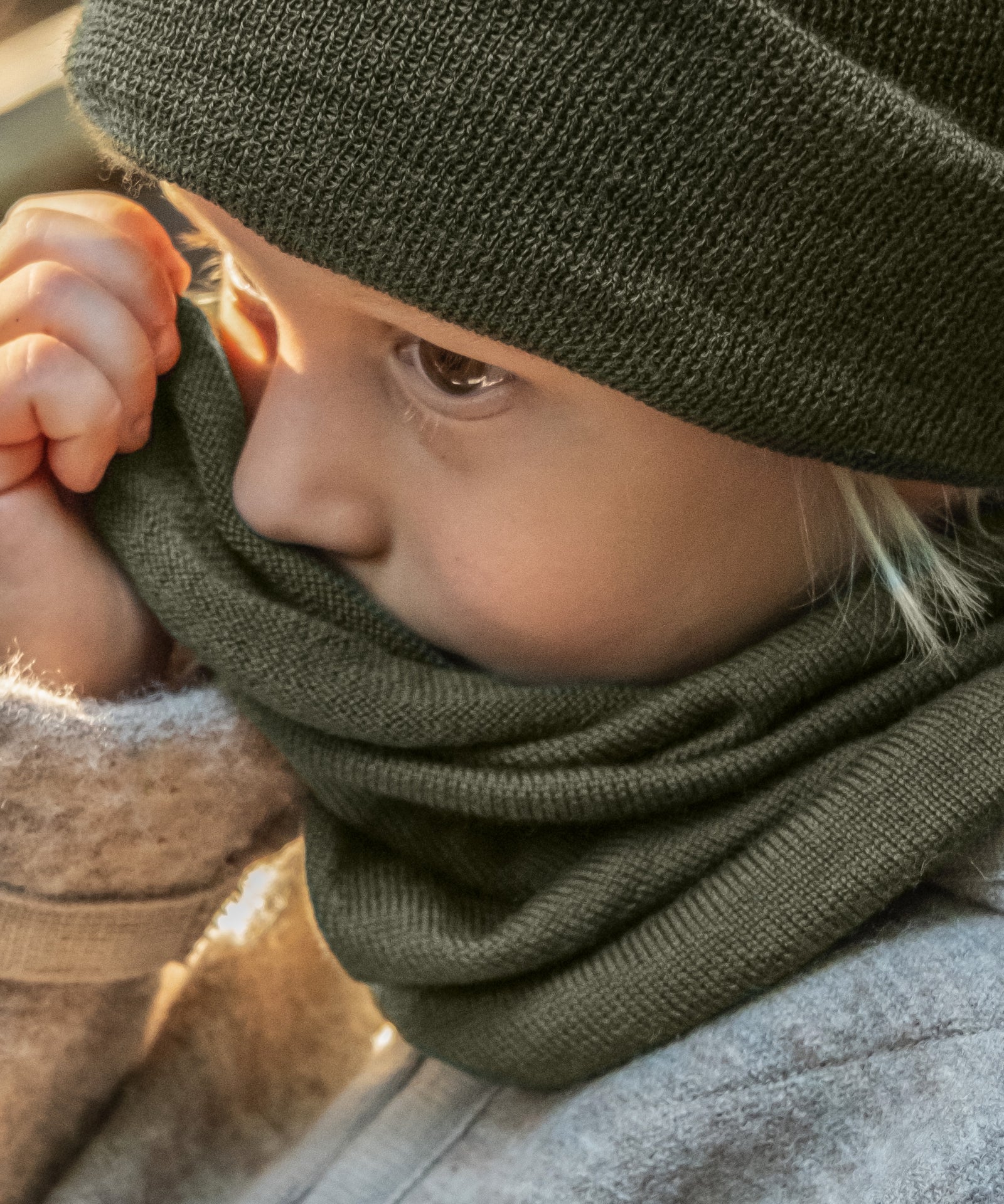 Kind mit Schlauchschal und Strickmütze in Oliv.