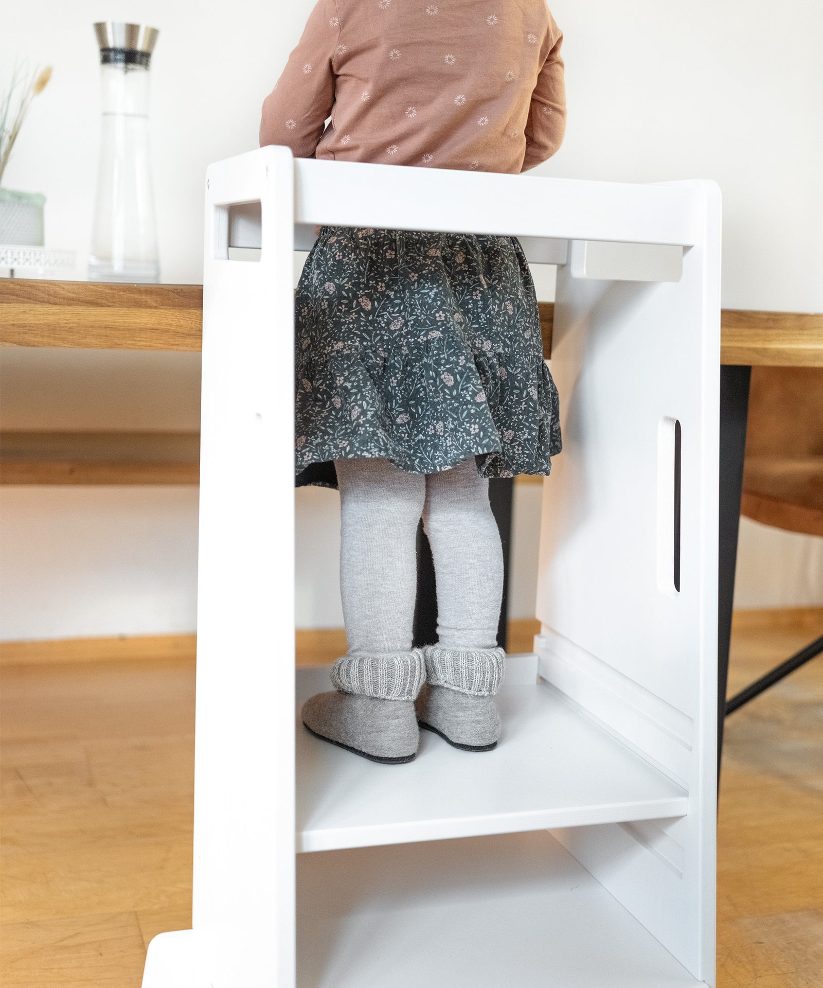 Rutschfest & sicher*Die robuste Filz-Latex-Sohle ist flexibel und rutschfest. Sie bietet auch auf rutschigen Flächen optimalen Halt.|Mädchen mit Kinder-Hausschuhen steht auf Lernturm.