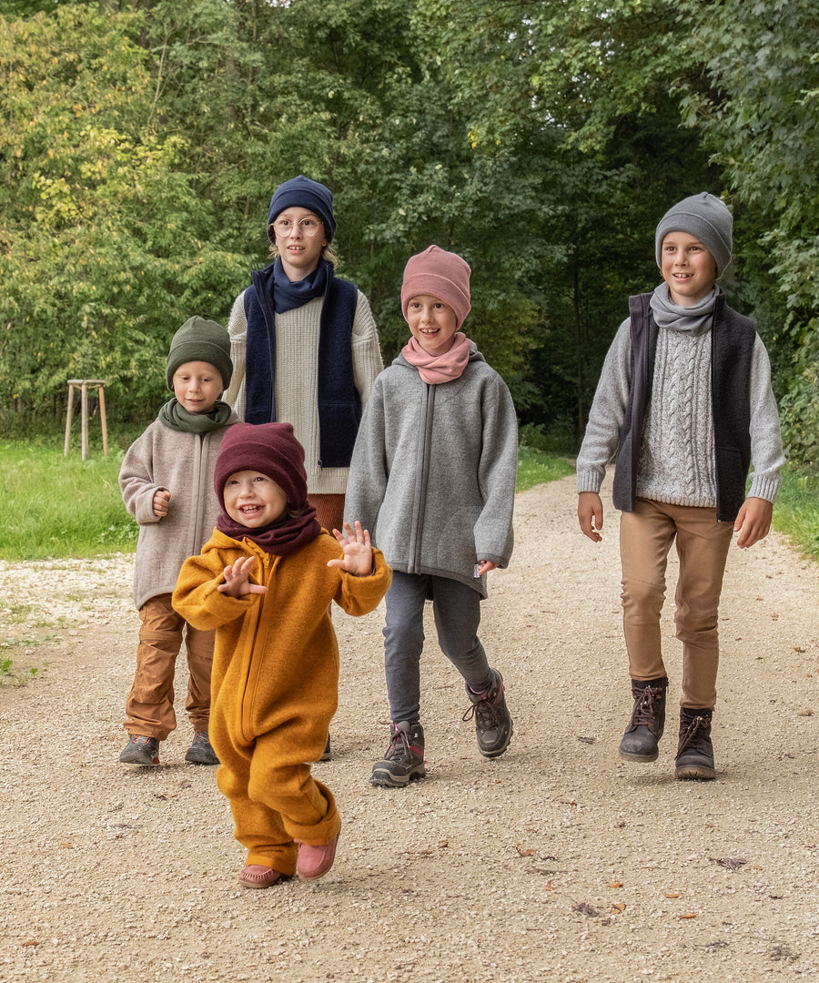Eine Größe für alle*Der Rippstrick ist sehr dehnbar und der Umschlagbund lässt sich variabel aufschlagen. So passt die Mütze allen von ca. 2 bis 12 Jahren.|Fünf Kinder von klein bis groß laufen auf einem Waldweg.