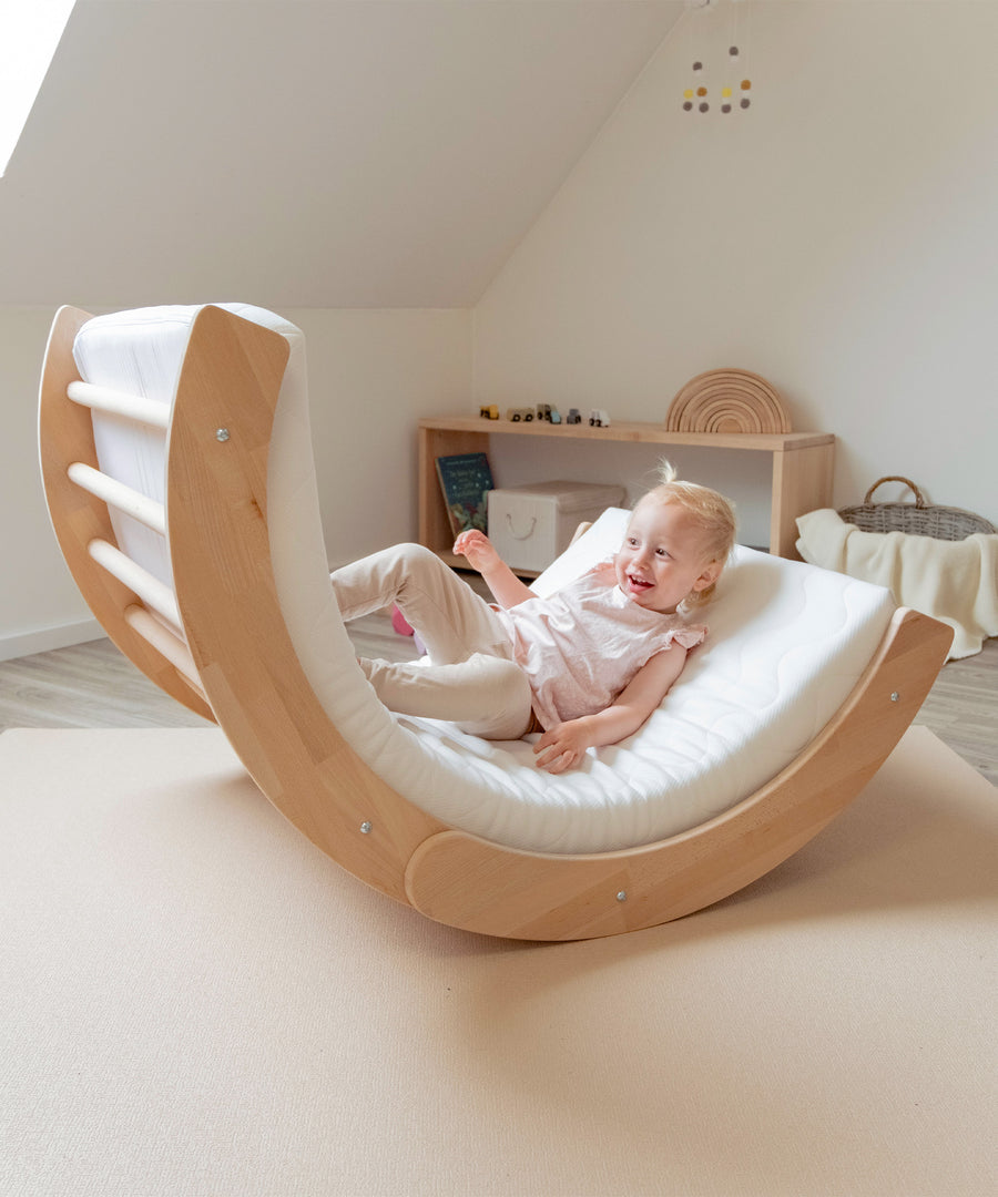 Spielspaß garantiert*Mit eingelegter Matratze und eingedrehter Kindersicherung kann der Kletterbogen umgedreht auch als Wippe verwendet werden.|Mädchen wippt im umgedrehten Kletterbogen.