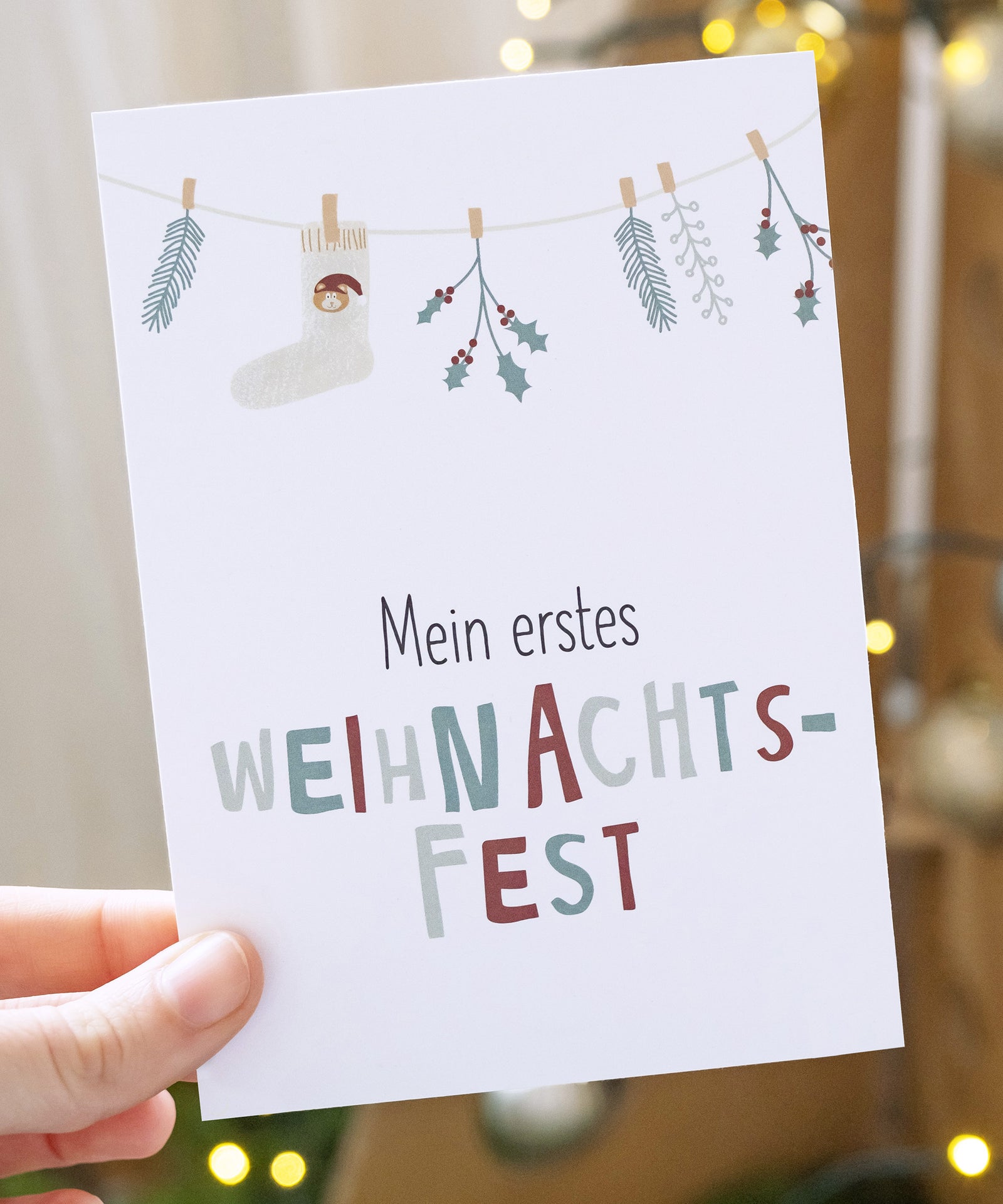 Meilensteinkarte mit Text "Mein erstes Weihnachtsfest" und weihnachtlicher Illustration.