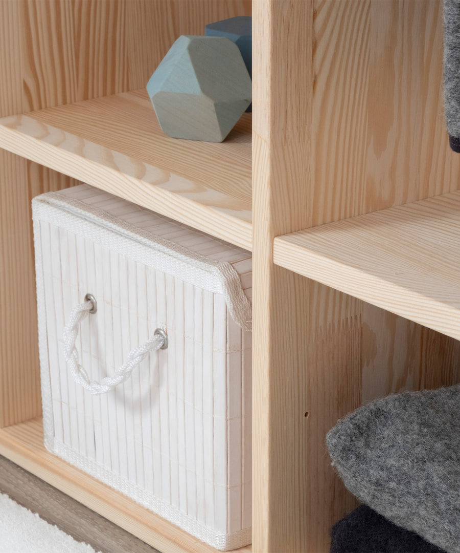 Abgerundete Kanten*Die Kanten am Montessori Kleiderschrank werden sorgfältig abgerundet.|Nahaufnahme der unteren Regale am Montessori Kleiderschrank Kiefer.