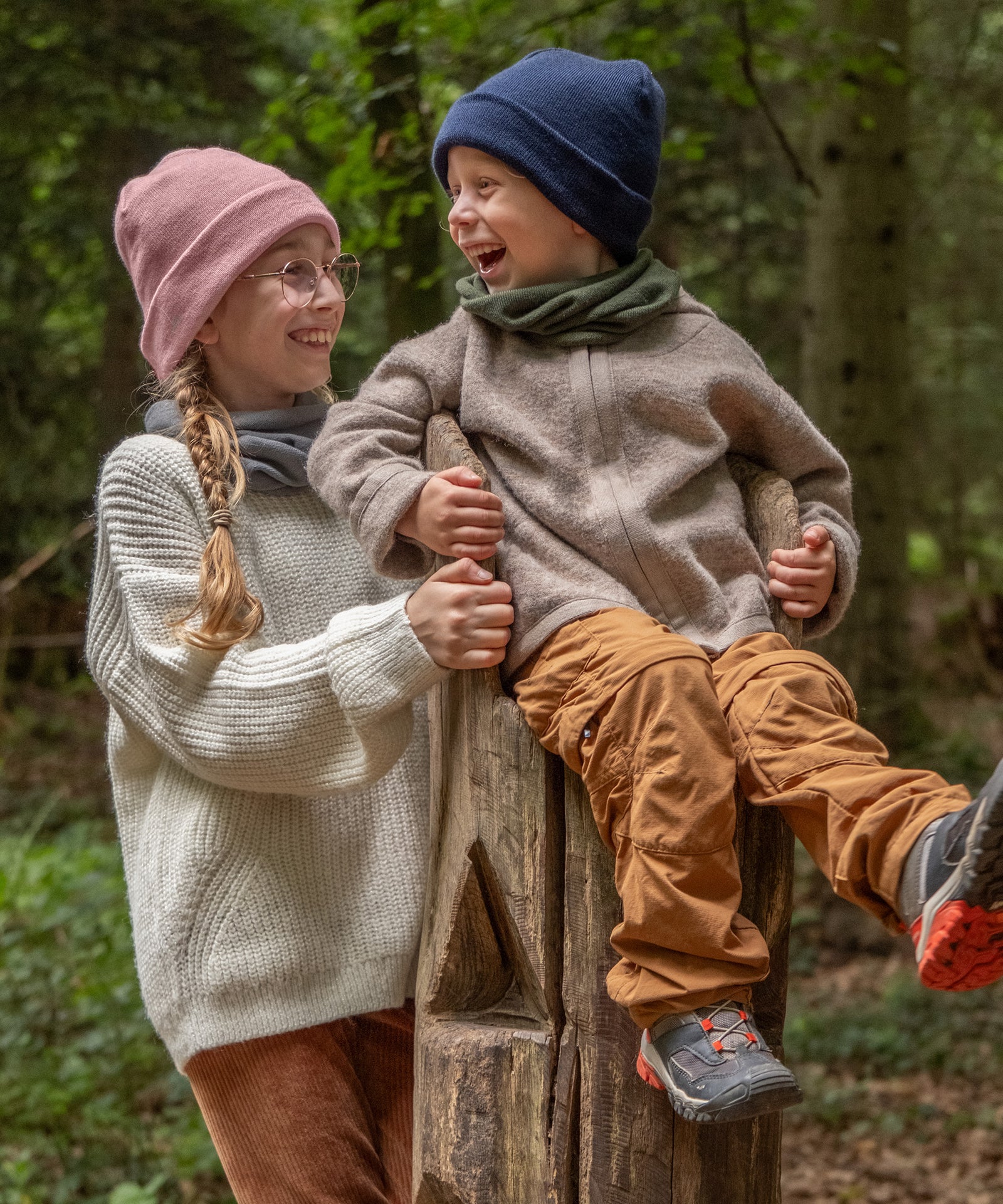 Vielseitig kombinierbar*Der Kinderschal im zeitlosen Design ist vielseitig kombinierbar und in fünf wunderschönen Farben erhältlich.|Zwei Kinder mit Schlauchschal und Strickmütze im Wald.