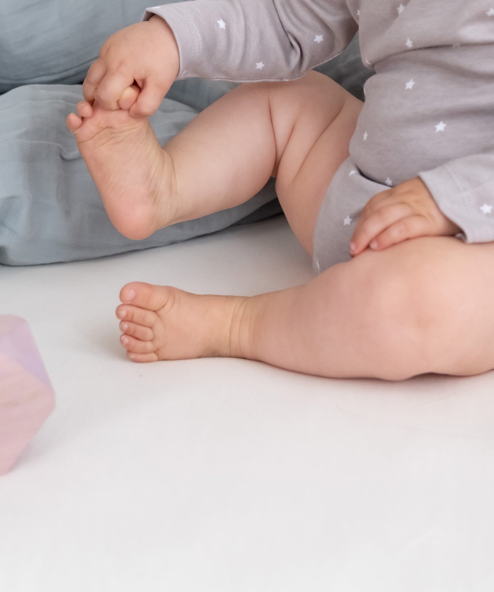 Sanft zu empfindlicher Babyhaut*Das Spannbettlaken aus reiner Bio-Baumwolle ist OEKO-TEX® STANDARD 100 zertifiziert und somit besonders hautfreundlich.|Nahaufnahme Baby auf Spannbettlaken.