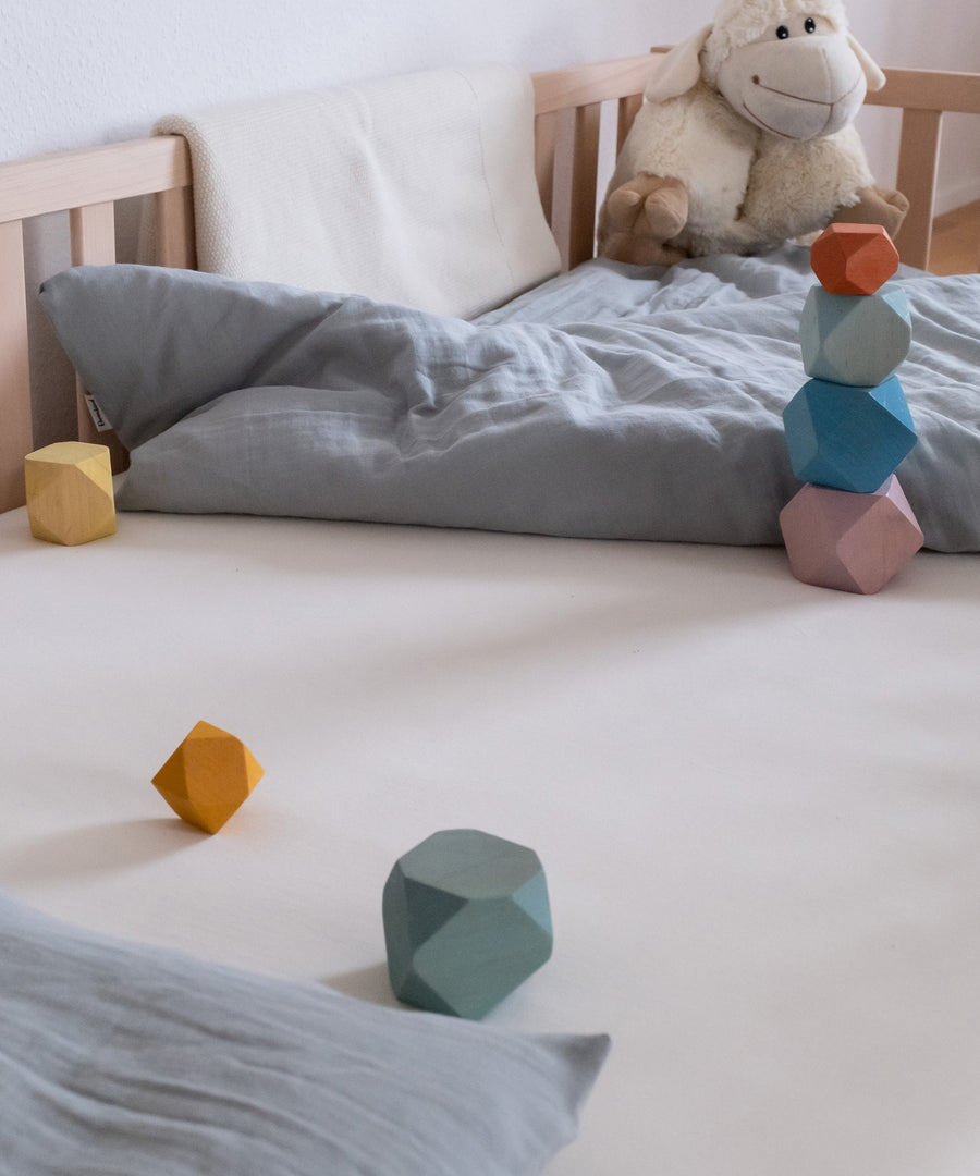 Praktisch!*Erhältlich in vier Farben und fünf Größen - passend vom Babybett 120 × 60 cm bis zu Betten der Größe 200 × 120 cm.|Bett bezogen mit Spannbettlaken, darauf Bettwäsche und Spielsachen.