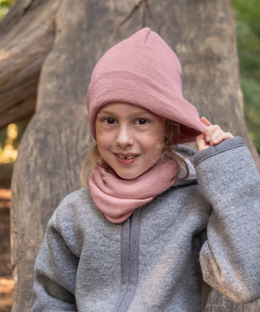 Superweich & kratzt nicht*Anders als bei normaler Schurwolle sind die Fasern der Merinowolle so fein, dass sie sich superweich anfühlen und nicht kratzen.|Mädchen mit Strickmütze und Schlauchschal in Rose.