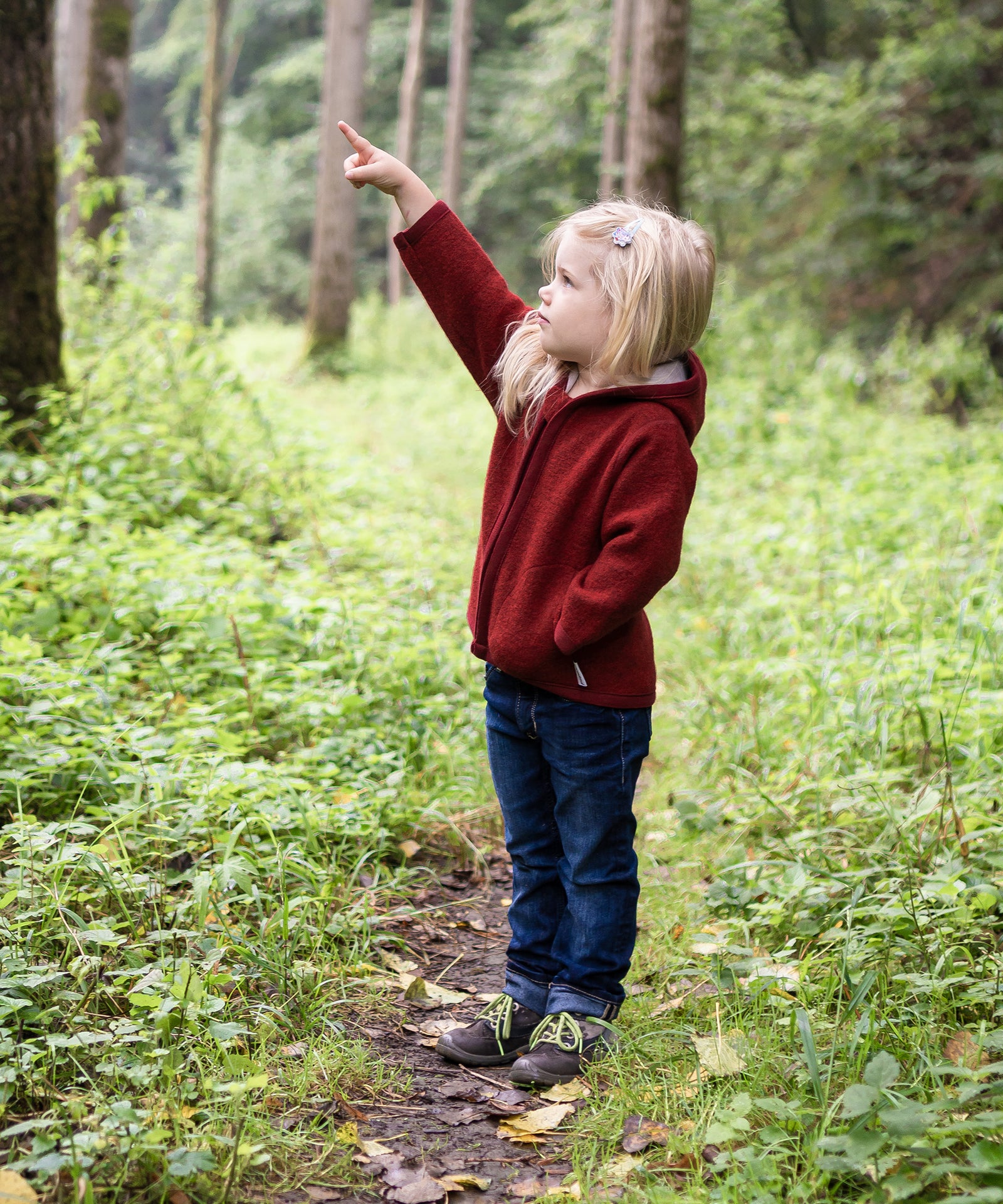 Mädchen mit roter Walkjacke im Wald.