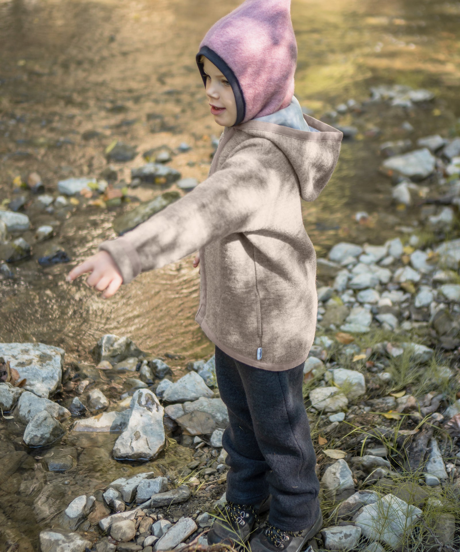 Mädchen mit Walkjacke beige spielt am Bach.