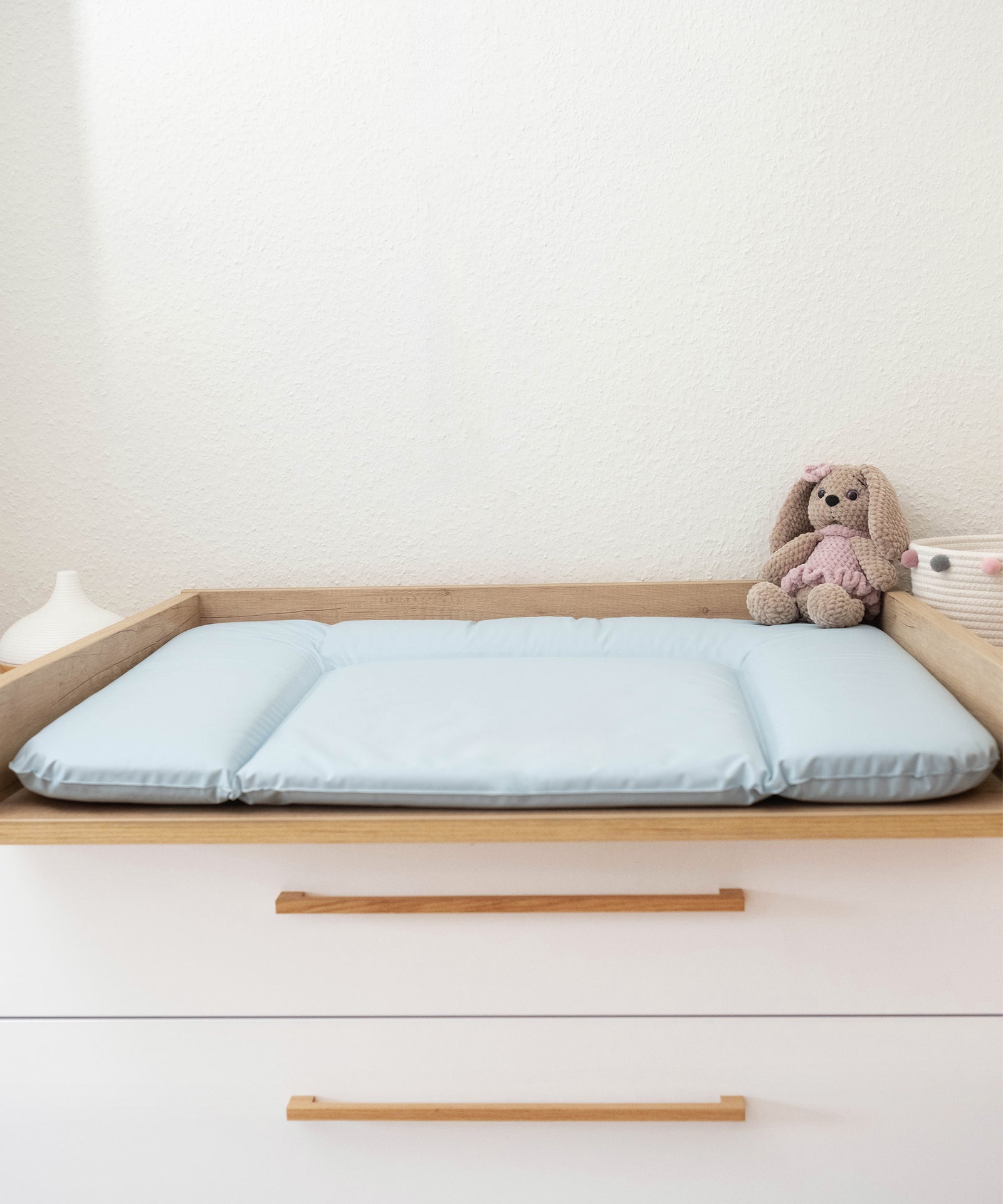 Sanft zur Haut*Die Auflage ist phthalatfrei, hygienisch und anti-allergisch - perfekt für die empfindliche Haut deines Babys.|Wickelauflage abwaschbar 72x85 cm in hellblau liegt auf Wickeltisch.
