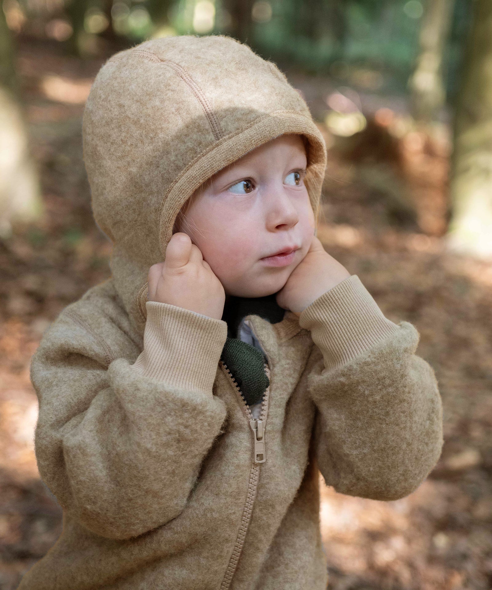 Praktische Kapuze*Die bequeme, mit hautfreundlicher Baumwolle gefütterte Kapuze wärmt den Kopf deines Kindes - perfekt für empfindliche Kinderhaut.|Mädchen zieht Kapuze des Wollfleece-Overalls auf.