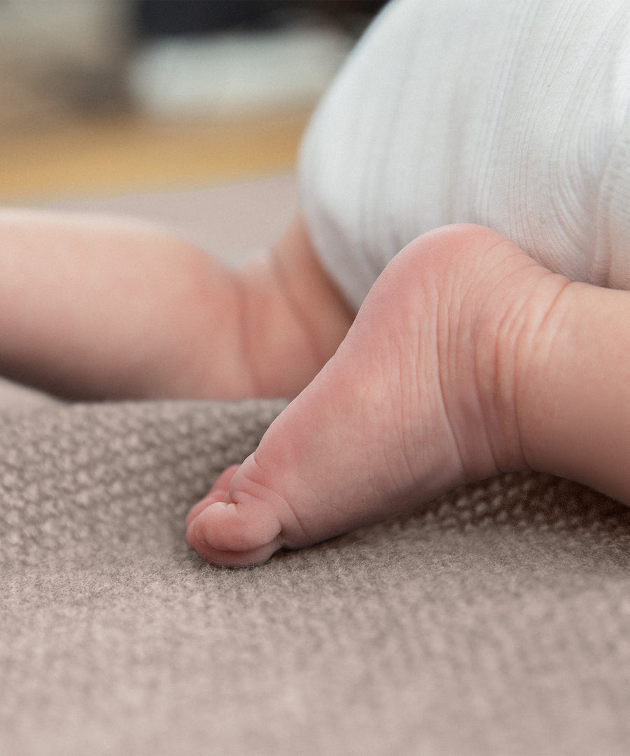 Babyfüße auf Lammwolldecke.