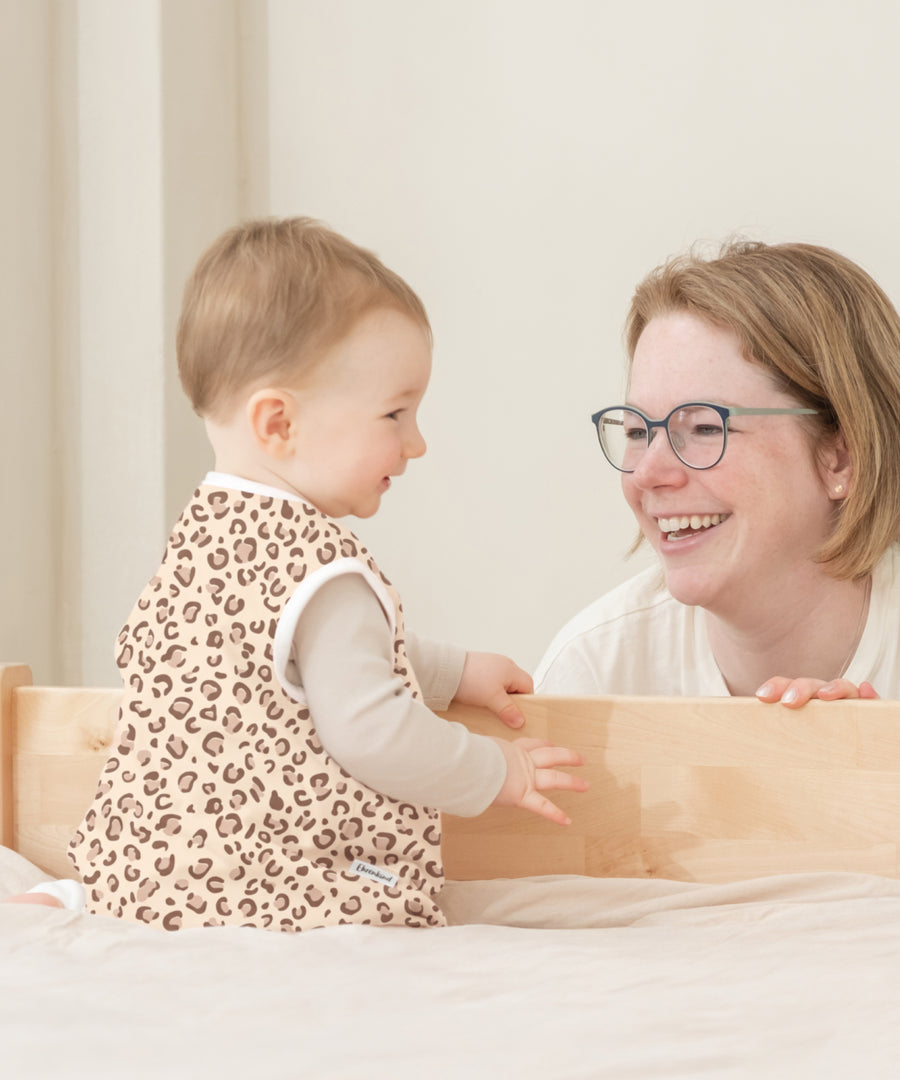 Baby trägt den Schlafsack im Leo-Muster.