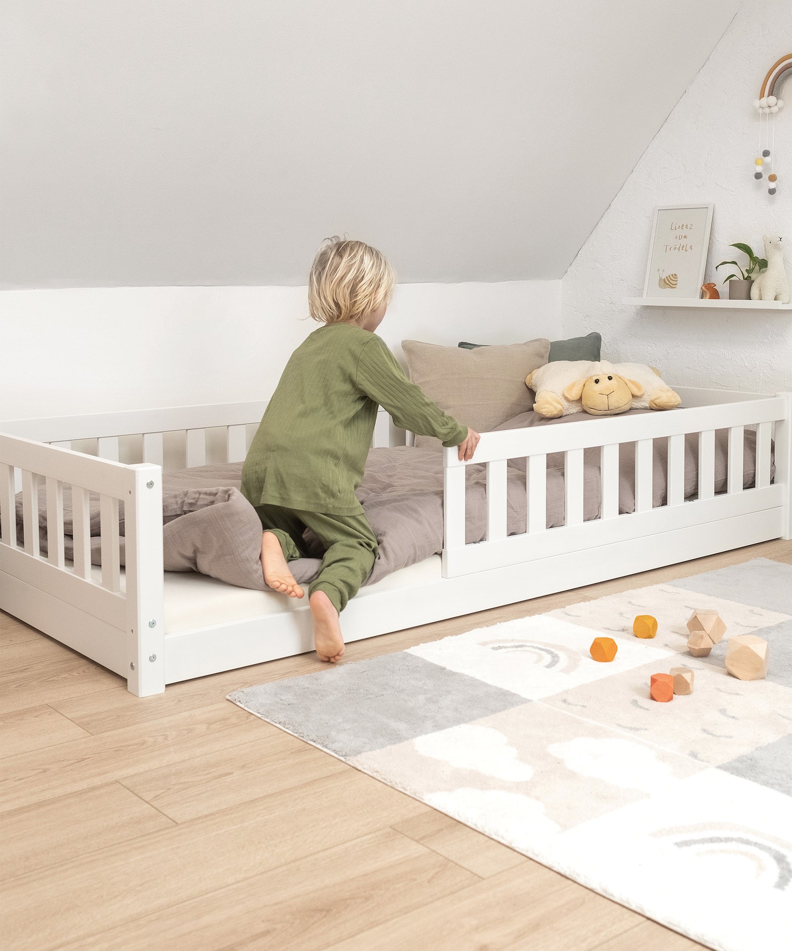 Leichter Einstieg*Das Bodenbett ermöglicht deinem Kind einen niedrigen und selbstständigen Ein- und Ausstieg.|Kind steigt in Bodenbett Kiefer, leicht dank niedriger Liegehöhe.