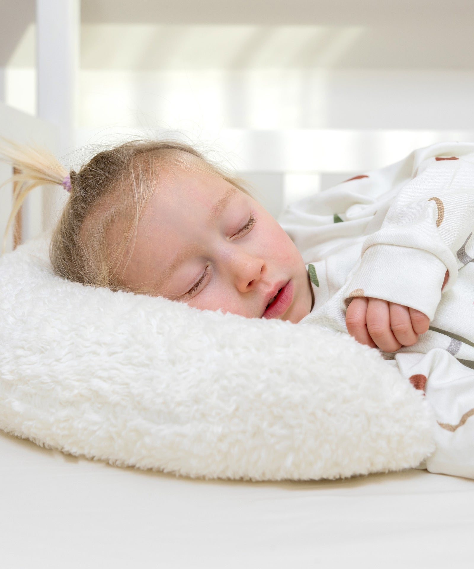 Kind schläft auf dem weichen Kuschelkissen mit Teddystoff.