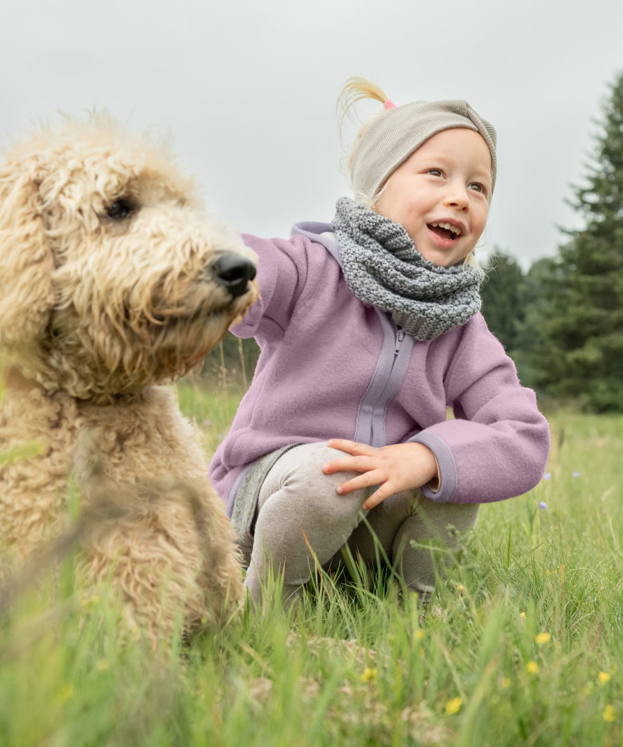 Perfekt für kühle Tage*Mit unserer Walkjacke ist dein Kind perfekt gerüstet für den Spielplatz, Waldspaziergänge und Outdoor-Abenteuer. Walkjacke in Flieder.|Kind trägt eine Walkjacke beim Spielen und Entdecken im Freien. W