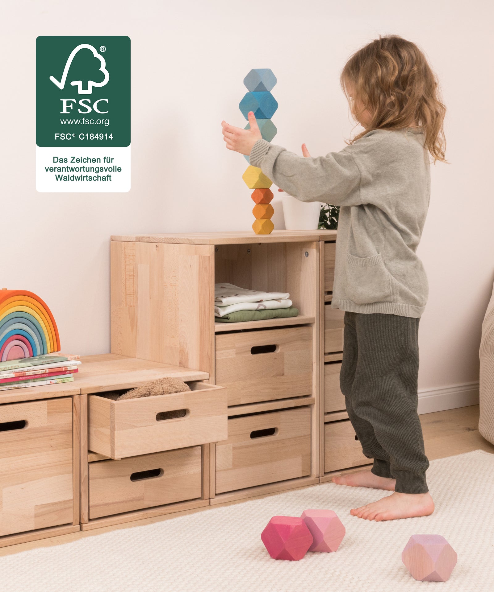 Selbstständig aufräumen*Durch die niedrige Höhe erreichen Kinder ihre Spielsachen selbst und lernen spielerisch Ordnung zu halten.|Kind räumt Spielsachen selbstständig in das  Regal ein.