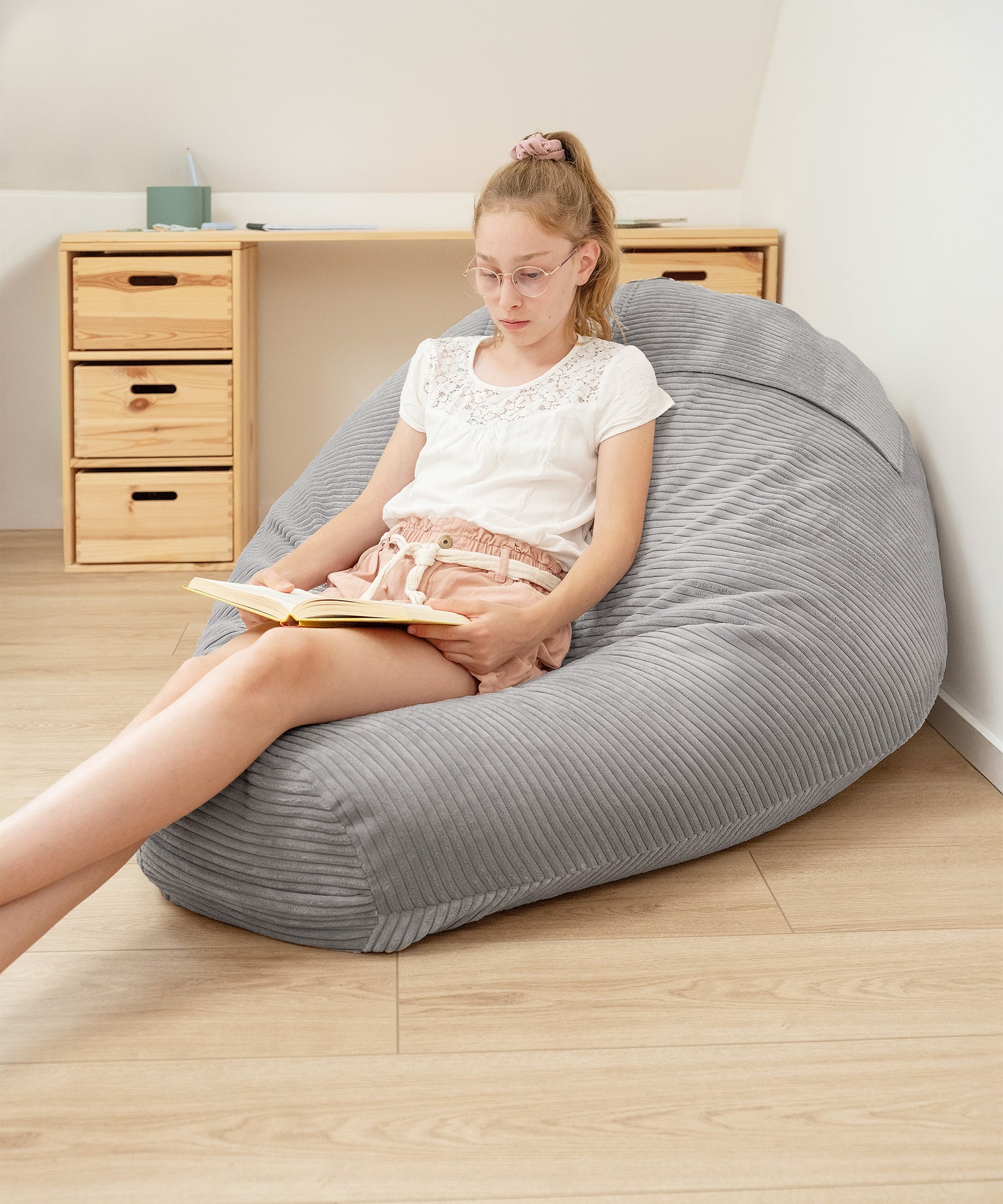Kind sitzt auf Sitzsack und liest ein Buch.