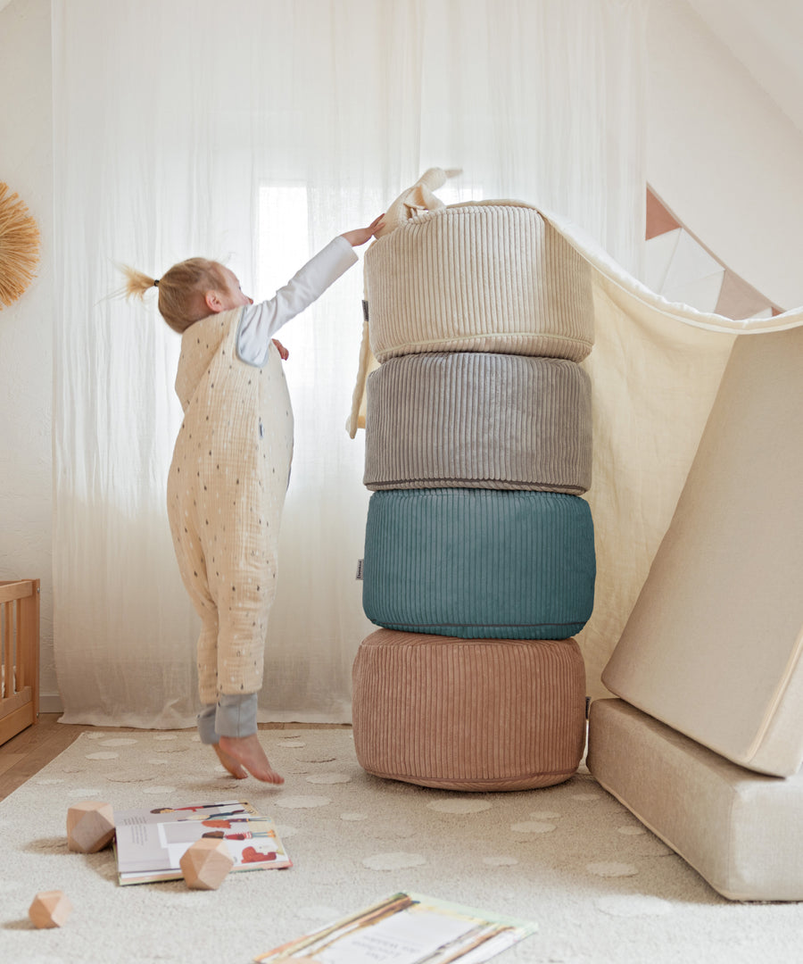 Kind baut einen Turm aus den Poufs